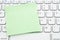 Blank green sticky note on a profile gray computer keyboard