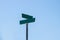 Blank green street signs on metal post with blue sky background.