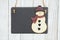 Blank hanging chalkboard with a snowman on weathered whitewash textured wood background