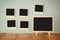 Blank instant photos hang over wooden textured background next to blank blackboard