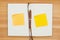 Blank journal with pen and  yellow sticky notes on a wood desk