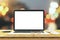 Blank laptop screen on wooden table with eyeglasses and cup of c