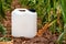 Blank mockup white plastic jug for herbicide chemical in cultivated corn field