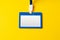 Blank nametag on a string on yellow background copy space