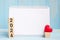 blank notebook and 2024 cubes with red heart shape decoration on blue wooden table background. New Year NewYou, Goal, Resolution,