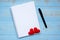 Blank notebook and pen with couple red heart shape decoration on blue wooden table background. Wedding, Romantic and Happy