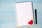 Blank notebook and pen with couple red heart shape decoration on blue wooden table background. Wedding, Romantic and Happy