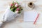 Blank notepad and bouquet of tulips wrapped in white paper