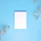 Blank notepad with gypsophila flowers on blue background