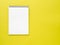 Blank notepad white page on yellow desk, color background. Top v