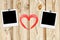 Blank old photos on clips and red heart on color wooden background