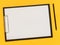 A blank paper on the balck tablet on yellow background. Flat lay