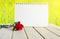 Blank paper calendar page and red rose flower over nature green field grass