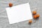 Blank paper card and dry physalis on gray linen cloth. Stylish minimalistic mockup scene. Modern autumn stationery still life.