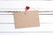 Blank paper card hanging on clothespins on white wooden background. Space for text.