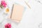 Blank paper notebook, pink flowers, golden stationery on marble background. Flat lay, top view feminine home office desk