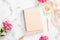 Blank paper notebook, pink flowers, pastel blanket and golden accessories on marble background. Flat lay, top view rose gold home