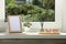 Blank photo frame with reed diffuser and home decor on white window sill