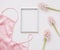 Blank photo frame, silk lingerie and pink flowers on white background. Styled feminine flat lay, top view, copy space