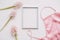 Blank photo frame, silk lingerie and pink flowers on white background. Styled feminine flat lay, top view, copy space