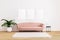 Blank picture or poster mockup.Pink sofa with black coffee table and plant in bright living room with white wall and wooden floor.