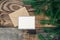 Blank postcard, envelope and fir branches on a wooden background, flat lay.