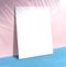 Blank poster at pastel pink wall and blue floor with palm leaf s