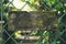 Blank rustic wooden sign hung on a steel fence.