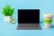 Blank screen computer tablet with keyboard case, desktop with coffee cup, potted plant, alarm clock