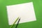 Blank sheet of paper space for design and lettering on a beautiful green background blue pencils. Perforated sheet torn from