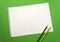 Blank sheet of paper space for design and lettering on a beautiful green background blue pencils. Perforated sheet torn from