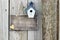 Blank sign with blue and white birdhouse next to tree