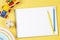 Blank sketchbook notebook with colored pencils and educational wooden kid toys and on yellow background. Top view