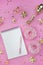 Blank spiral notebook with white pen on a pink background with golden confetti and bows, pink donuts. Fashionable color and style