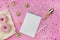 Blank spiral notebook with white pen on a pink background with golden confetti and bows, pink donuts. Fashionable color and style