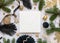 Blank square envelope between black and golden Christmas decorations and fir tree branches top view