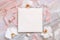 Blank square envelope near white orchid flowers and silk ribbons on marble, mockup