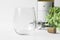 Blank stemless wine glass with wine bottle, bottle opener and greenery.