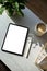 Blank tablet mockup on table. Aesthetic home office desk with tablet, pen, cup of coffee, office stationery, green plant