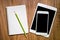 blank tablet and phone with an empty folder on a wooden workspace