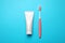 Blank tube of toothpaste and brush on color background