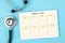 The Blank weekly plan notice block and medical stethoscope on blue colour background