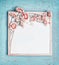 Blank white chalkboard and pretty pastel color flowers bunch on turquoise shabby chic background, top view