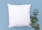 Blank white cushion mock up on blue background with eucalyptus sprig right