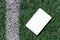 Blank white empty screen,mockup.PC tablet flat lay on the sport synthetic green grass outdoors background.Top view.Mockup