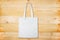 Blank white fabric bag on wooden background. Plain white tote bag on natural wooden texture