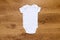 Blank white gender neutral babygrow onesie on a warm wooden background