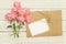 blank white greeting card with pink rose flowers bouquet and envelope with flower buds on white wooden background.