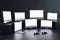 Blank white monitors of modern computers and laptops with blank space in home game studio with dark wall and joysticks on glossy