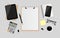Blank white paper on clipboard with digital tablet, notebook, pen, black metallic paper clips, calculator, coffee cup, eyeglasses